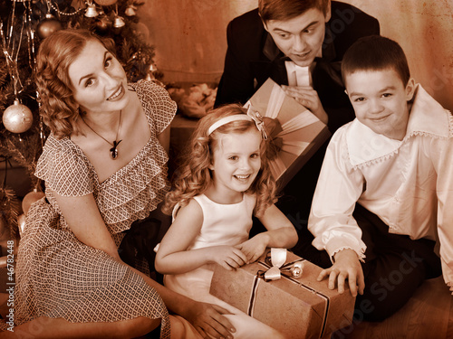 Photo: Family with children receiving gifts under Christmas tree. Family with children receiving gifts under Christmas tree.
