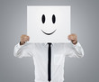 Young businessman holding card with a happy face on it