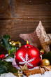 candle and holly in snow before wooden board
