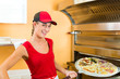 Frau schiebt die Pizza in den Ofen