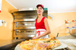 Frau schiebt die Pizza in den Ofen