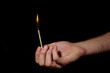 Photo: Hand holding burning match stick on black background Hand holding burning match stick on black background