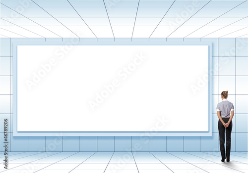 Photo: Business person standing near a blank billboard Business person standing near a blank billboard