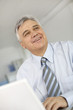 Portrait of senior businessman in office working on laptop