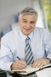 Portrait of senior businessman writing on agenda