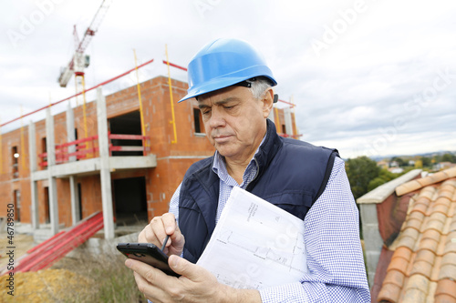 Photo: Construction manager on building site using smartphone Construction manager on building site using smartphone