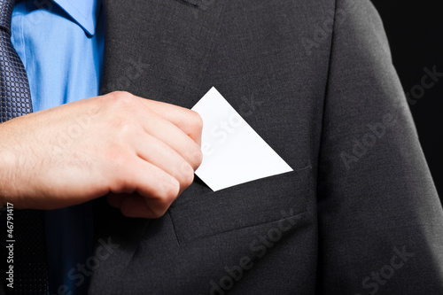 Photo: Business man puts a business card in the poket Business man puts a business card in the poket