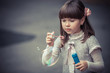 Portrait of funny lovely little girl blowing soap bubble