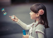 Portrait of funny lovely little girl blowing soap bubble