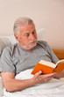 Senior im Altenheim beim Buch lesen im Bett