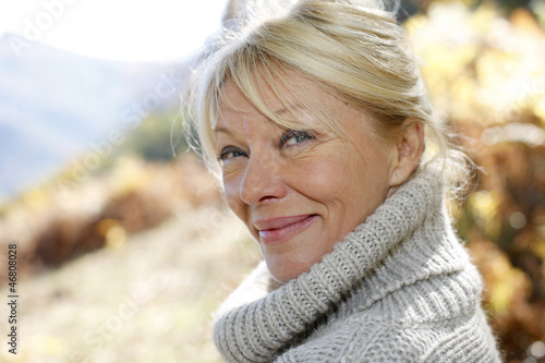 Photo: Portrait of senior woman leaning against tree Portrait of senior woman leaning against tree