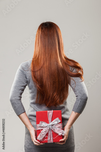 Photo: Woman hiding a gift behind her back Woman hiding a gift behind her back