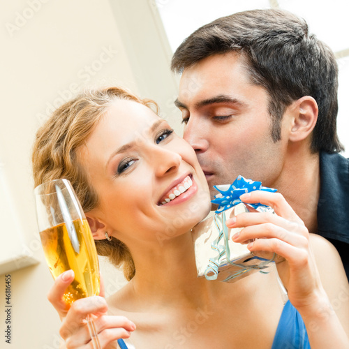 Photo: Cheerful amorous couple with gifts, indoors Cheerful amorous couple with gifts, indoors