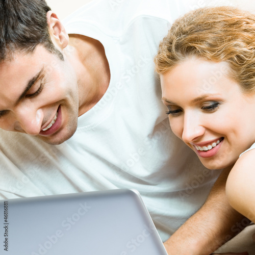 Photo: Cheerful couple with laptop, at home Cheerful couple with laptop, at home
