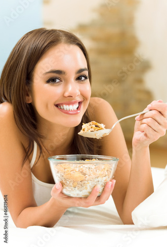 Photo: Young woman eating cereal muslin (flakes) Young woman eating cereal muslin (flakes)