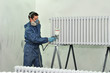 Worker painting white radiator.