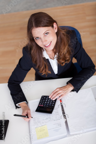 Photo: Smiling accountant sitting at her desk working Smiling accountant sitting at her desk working