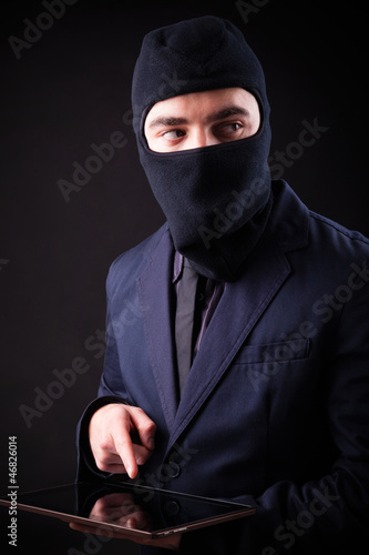 Photo: Closeup portrait of a hacker stealing data from digital tablet Closeup portrait of a hacker stealing data from digital tablet