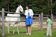 Young woman and her little son feeding white lama