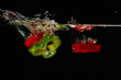 Slices of red and green peppers falling into water with splash