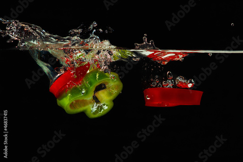 Photo: Slices of red and green peppers falling into water with splash Slices of red and green peppers falling into water with splash
