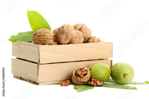 Photo: walnuts with green leaves in woooden crate, isolated on white walnuts with green leaves in woooden crate, isolated on white