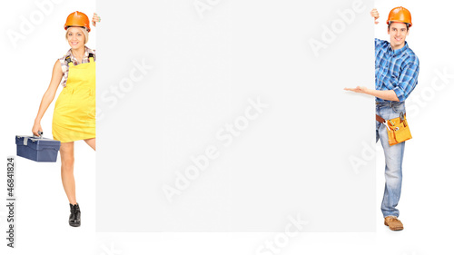 Photo: Female and male worker posing behind a panel Female and male worker posing behind a panel