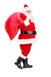 Santa Claus walking with bag full of gifts og his back