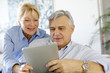 Photo: Modern senior couple websurfing on tablet Modern senior couple websurfing on tablet