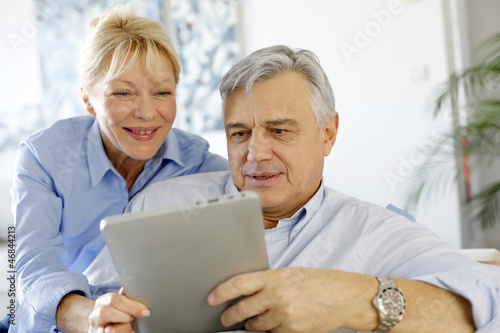 Photo: Modern senior couple websurfing on tablet Modern senior couple websurfing on tablet