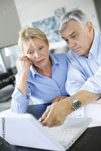 Photo: Senior couple inquiring bank website for help Senior couple inquiring bank website for help