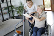 Photo: Young woman helping disabled lady at home Young woman helping disabled lady at home
