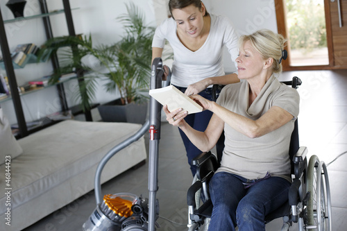 Photo: Young woman helping disabled lady at home Young woman helping disabled lady at home