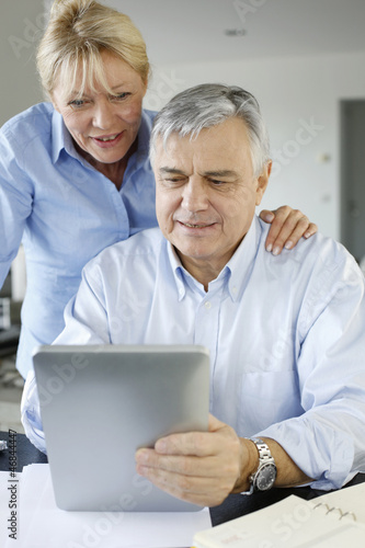 Photo: Senior couple looking at bank account on digital tablet Senior couple looking at bank account on digital tablet