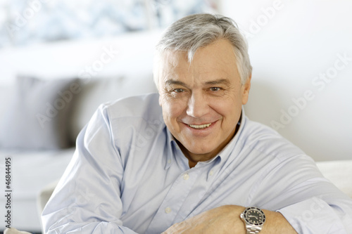 Photo: Portrait of senior man relaxing in sofa at home Portrait of senior man relaxing in sofa at home