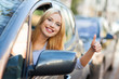 Young woman doing thumps-up in car