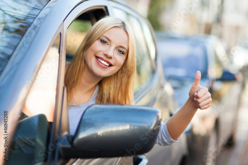 Photo: Young woman doing thumps-up in car Young woman doing thumps-up in car