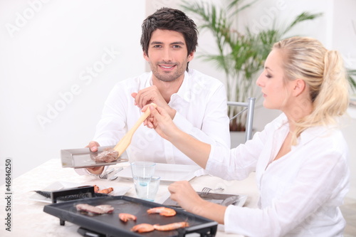 Photo: Couple using a table-top grill Couple using a table-top grill