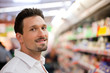 Mann steht im Supermarkt vor einem Regal