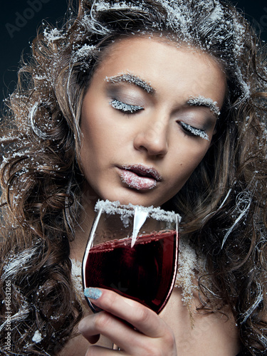 Photo: Portrait of young woman with snow make-up with a glass of wine. Portrait of young woman with snow make-up with a glass of wine.