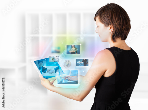 Photo: Young woman browsing pictures on modern tablet Young woman browsing pictures on modern tablet