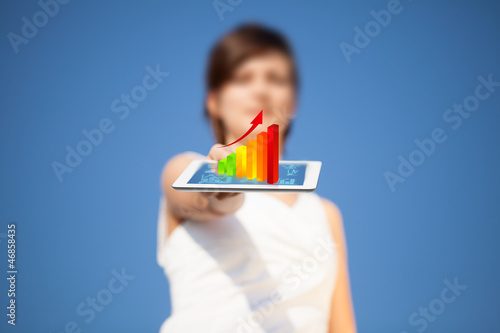 Photo: Young woman looking at modern tablet with abstract light and var Young woman looking at modern tablet with abstract light and var