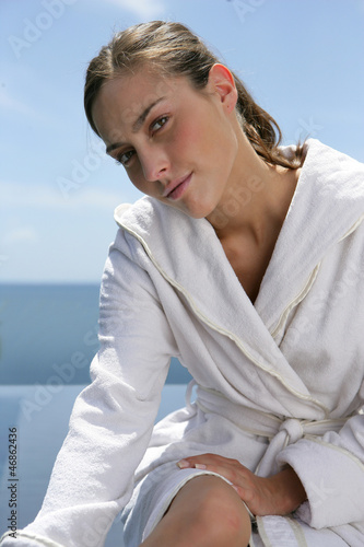 Photo: Woman sat at the seaside in white robe Woman sat at the seaside in white robe