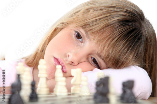 Photo: Bored girl playing chess Bored girl playing chess