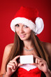 beautiful young brunette woman wearing a Santa's hat holding a b