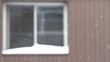 Window of apartment in a winter day. Slowly falling snow