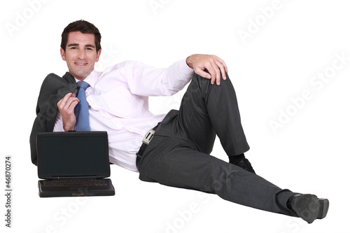 Photo: Businessman lying on the floor with his laptop Businessman lying on the floor with his laptop