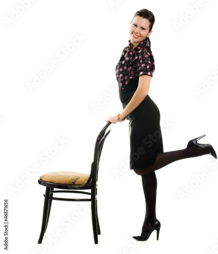 Photo: Pretty happy retro woman standing with a chair. Pretty happy retro woman standing with a chair.