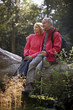 A mature couple sitting on a tree trunk resting
