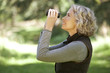 A mature woman outdoors, looking through a pair of binoculars